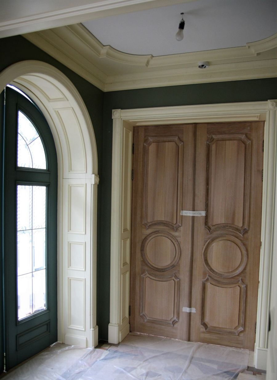 Резные распашные двери из массива орехового оттенка в интерьере прихожей
